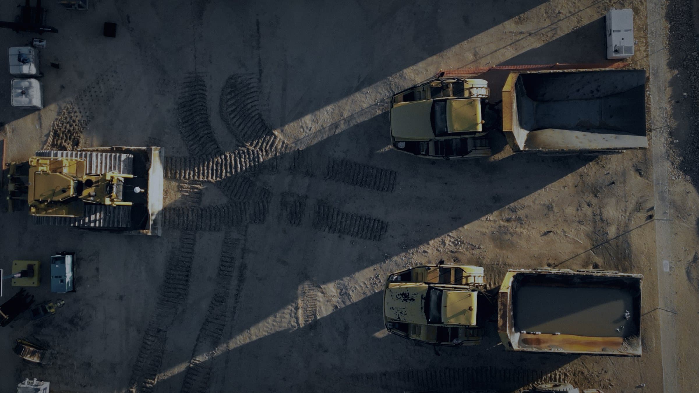 Dump trucks and a dozer on an earthworks site, seen from directly above.